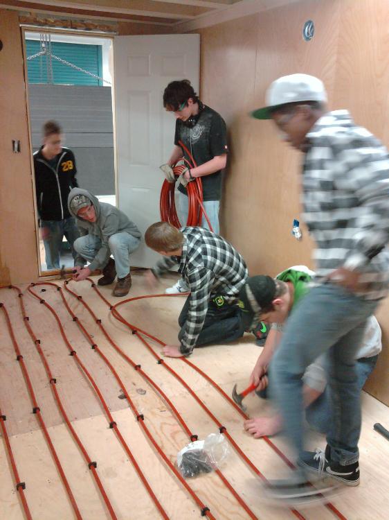 Students installing in floor heat to the house.