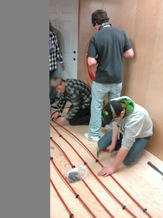 Students installing in floor heat in the house.