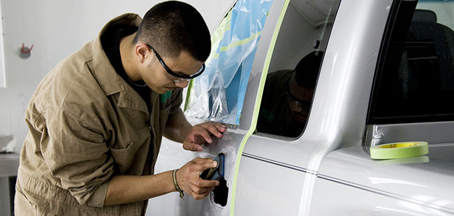 Student repairs a dent in a pickup truck