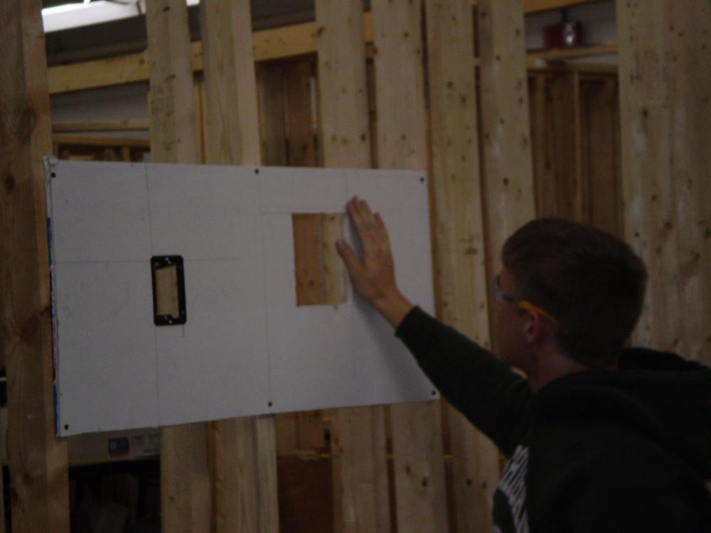 Marking and cutting boxes into drywall.